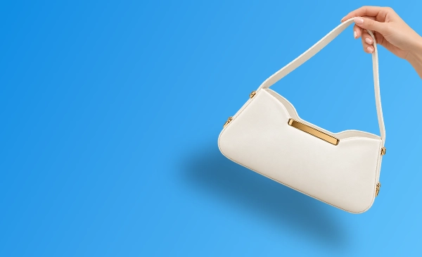 Ivory shoulder bag with gold-tone hardware held by hand